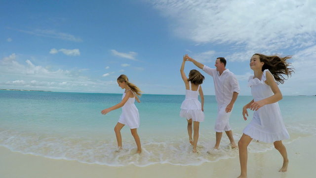 Happy Caucasian family playing and laughing on beach vacation 