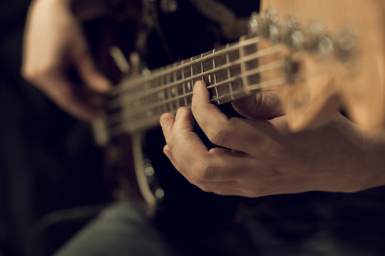 Hand of a man playing bass guitar