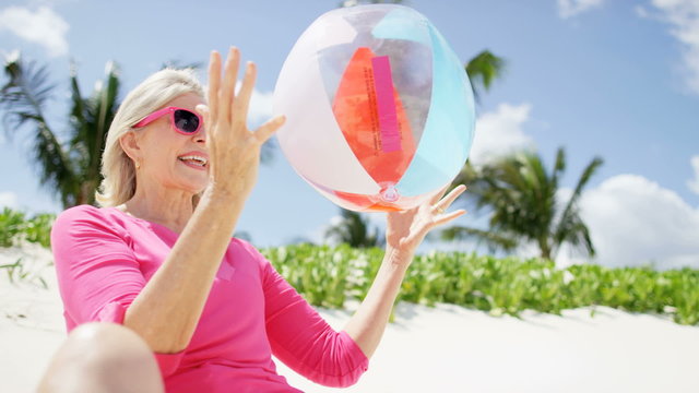 Retired Caucasian female having fun outdoors with a beach ball