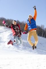 Happy young couple jumping in ski resort