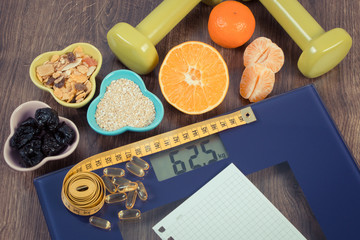 Digital scale with tape measure, tablets, dumbbells, fruits, muesli, slimming concept