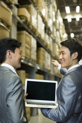 Business partners with laptop in logistic warehouse