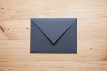 A grey envelope on the wood desk, top view at the studio.
