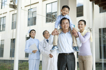 Young Family Stands in a Hospital Corridor With a Doctor and a Nurse