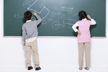 Elementary schoolchildren writing on blackboard in classroom