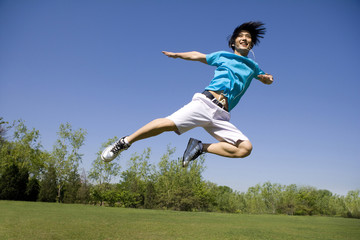 Fototapeta na wymiar Young man jumping in air at park