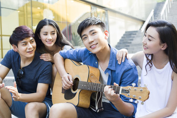 Young man playing guitar with his friends