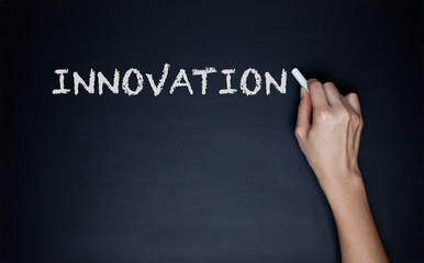 innovation word in white chalk handwriting on blackboard