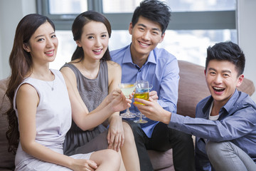 Happy young friends drinking cocktail in living room