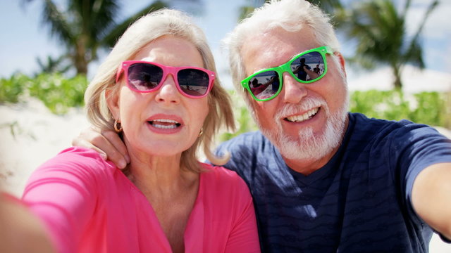 Caucasian senior couple in bright clothing enjoying beach vacation