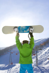 Rear view of a young man posing with his snowboard