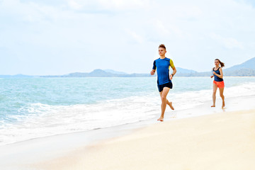 Healthy Lifestyle. Athletic Runner Couple Running On Beach, Training For Marathon. Sporty Fit People Jogging Near Sea ( Ocean ) During Outdoor Workout. Sports And Fitness. Exercising. Health Concept