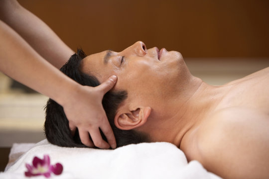 Spa attendant giving a head massage to a man