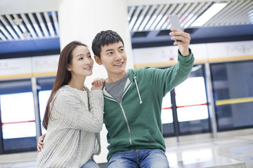 Young couple taking self portrait at subway station
