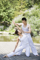 Yoga instructor helping woman with pose