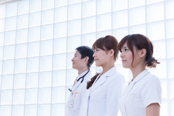 病院内で微笑む女性看護師と女性医師・男性医師