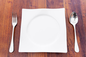 white plate Spoon and fork on a brown wooden table