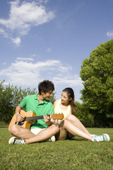 Portrait of a young couple at the park with a guitar