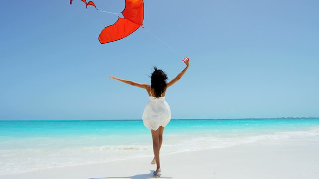 Smiling African American girl playing with red kite on beach 