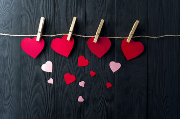Different hearts with clothespins on background