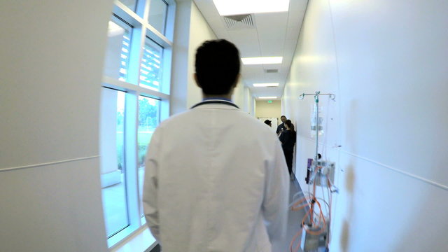 Young Asian American male doctor greeting team in hospital