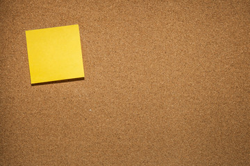 yellow reminder sticky note on cork board, empty space for text