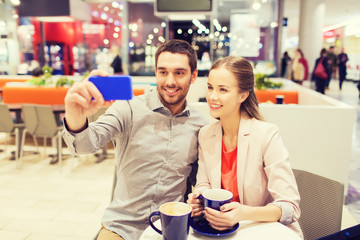 happy couple with smartphone taking selfie in mall