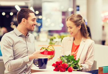 happy couple with present and flowers in mall