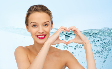 smiling young woman showing heart shape hand sign