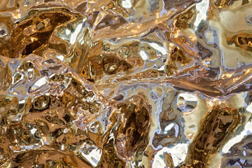 liquid metal reflective sculpture closeup in a warm light