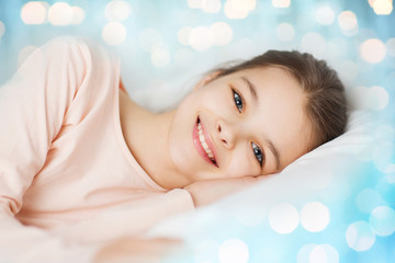 Obraz na płótnie Canvas happy smiling girl lying awake in bed over lights