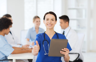 happy doctor with tablet pc over team at clinic