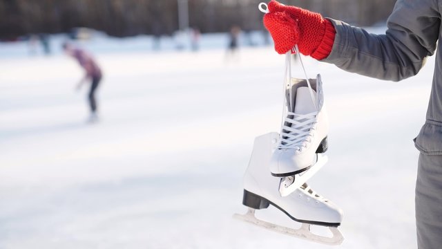 ice skating winter woman holding ice skates outdoors in snow. 