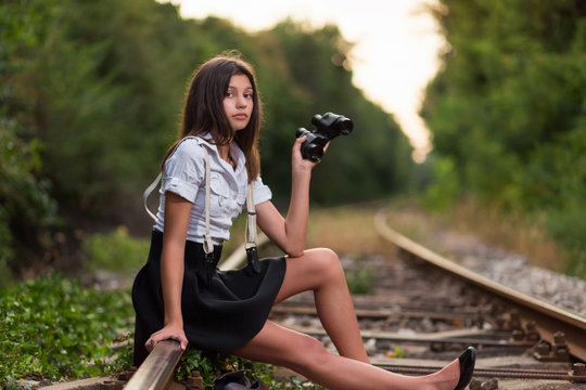 Girl with binocular sitting on the railway line