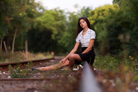Beautiful young woman sitting on the railway line