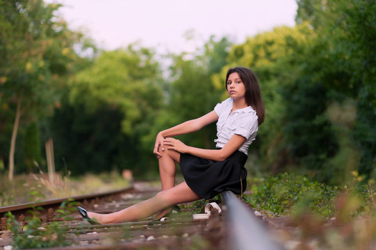 Beautiful girl sitting on the railway line