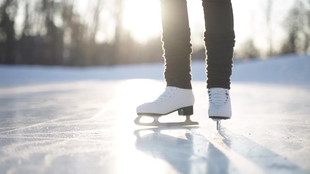 Young woman skating on ice with figure skates outdoors in the snow