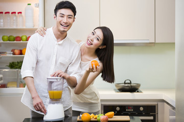 Young couple using juicer in kitchen