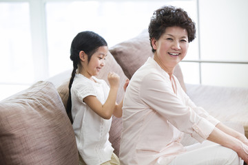 Cute girl massaging grandmother's back