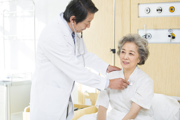 Doctor using stethoscope on patient in hospital