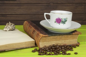 Cup of hot coffee and old book. Relaxing at the coffee. Studying old books. Place for your text. Cup of coffee on a wooden table. Vintage old books on wooden deck tabletop with cup of coffee.
