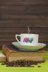 Cup of hot coffee and old book. Relaxing at the coffee. Studying old books. Place for your text. Cup of coffee on a wooden table. Vintage old books on wooden deck tabletop with cup of coffee.
