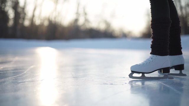Young woman skating on ice with figure skates outdoors in the snow