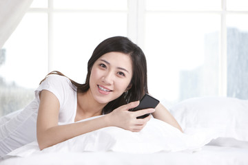 Young woman holding cellphone at home
