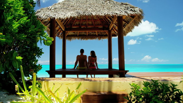 Caucasian couple sitting in a Caribbean tiki hut