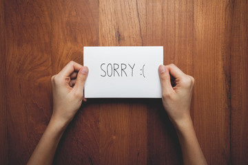 a woman with a sign in her hands with the words sorry