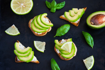 Toast with avocado, cream cheese curd and lime on a dark backgro