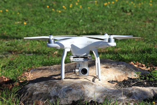 Drone equipped with high resolution 4K video camera placed on a green field ready for take off