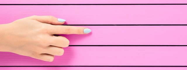 Female hand pointing on pink background