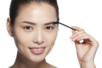  Headshot of young woman applying makeup